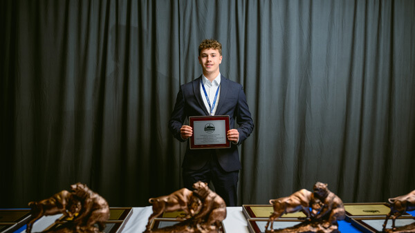 A student recognized as awardee in the Undergraduate Fixed Income category poses with his award during the Forum Poster Competition Awards Ceremony.