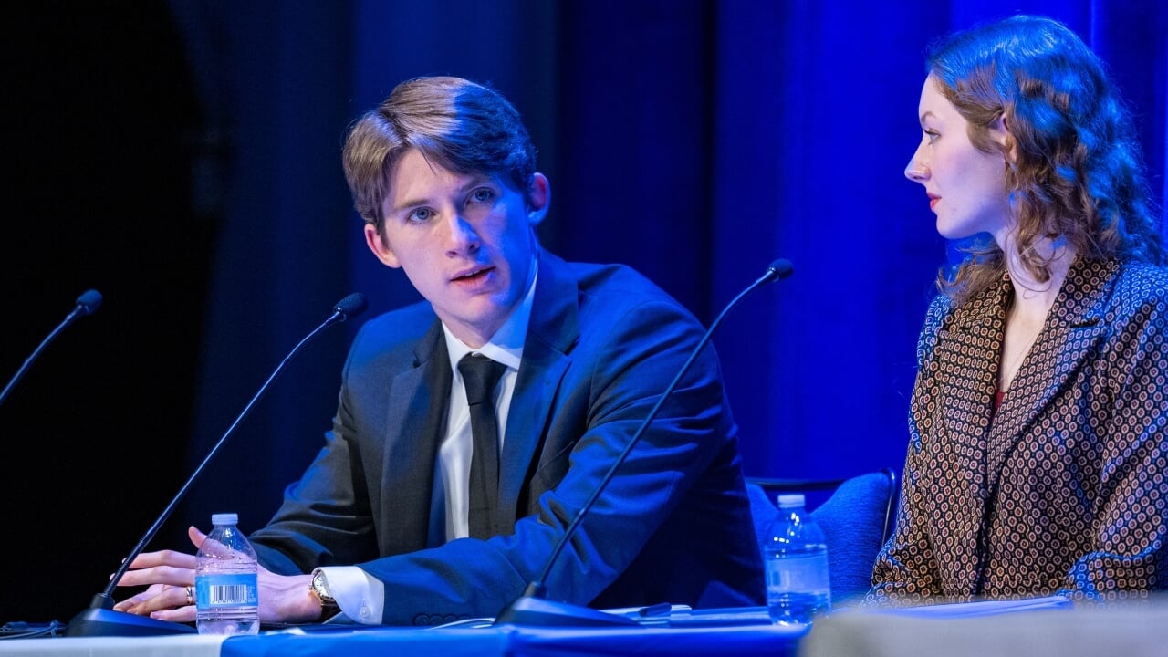 Student moderator speaks into a microphone during a keynote panel.