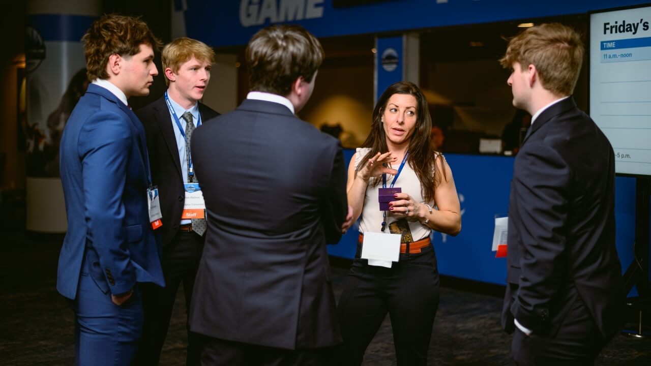 GAME Fourm attendees speak to a female executive.
