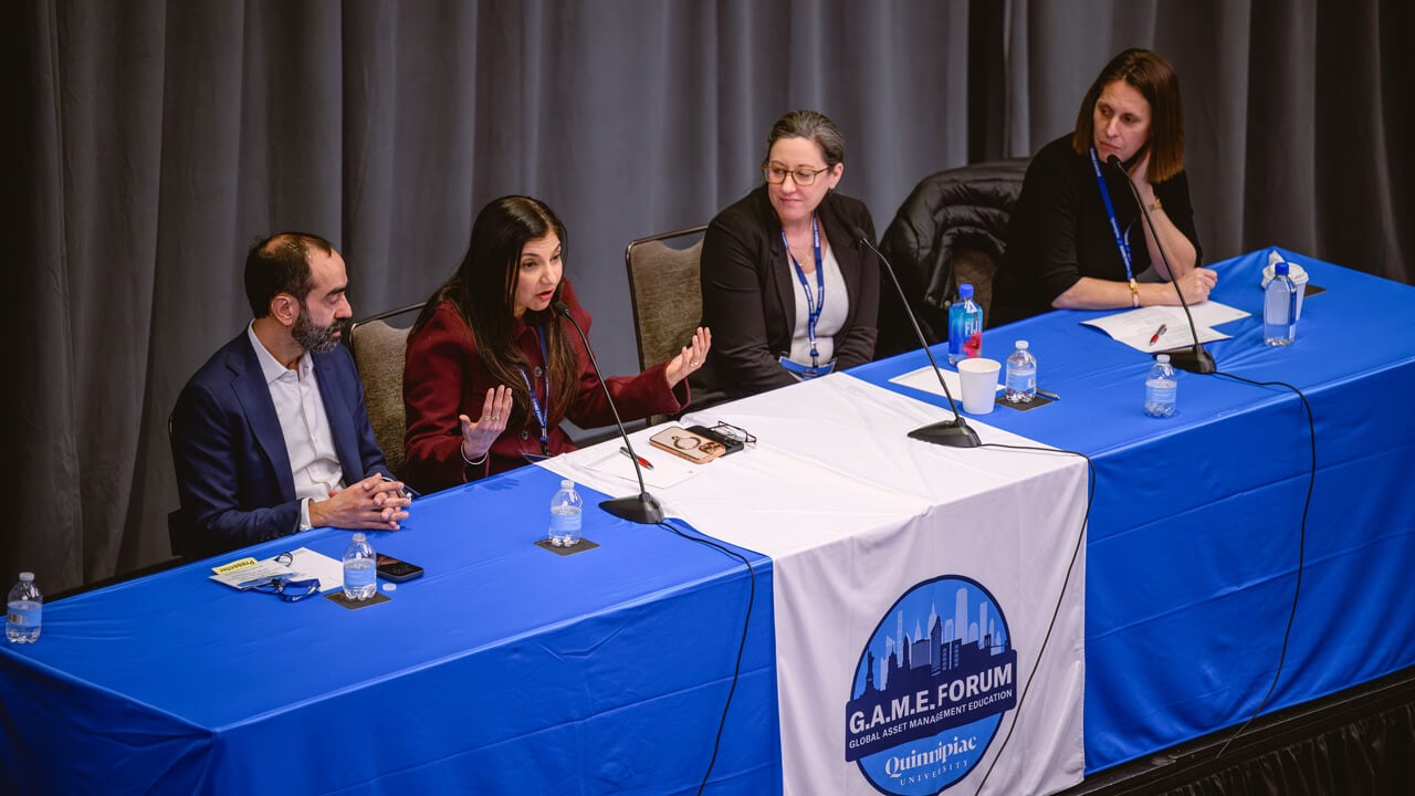An angled shot from above of Juan Carlos Artigas, Jitania Kandhari, Katherine Santiago, and Katrina Dudley seated at a Forum panel table .