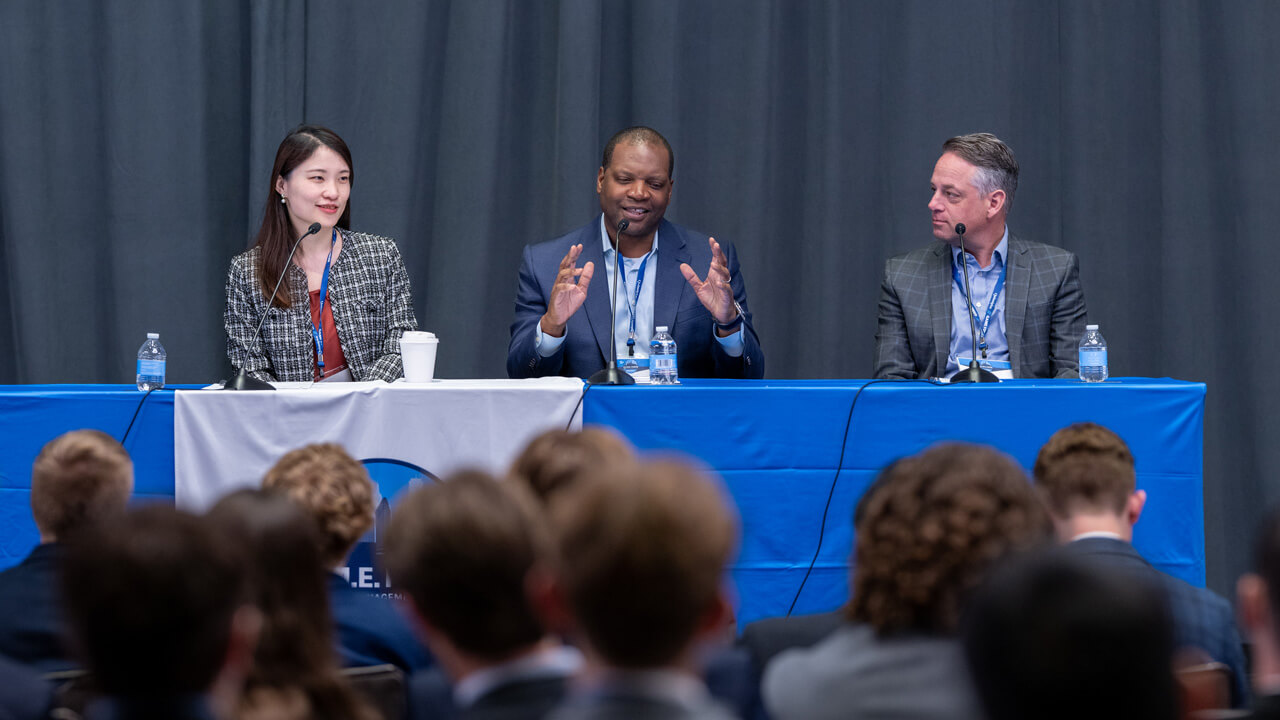 Jasmine Fan, Bobby Barnes, and Noah Kroll seated at a Forum panel table with Barnes speaking into a microphone.