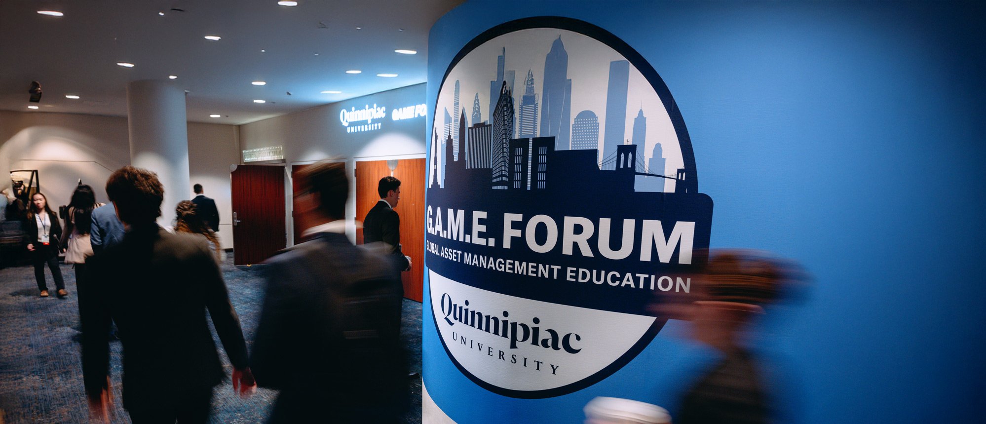 Students walk by signage at the GAME Forum between sessions.