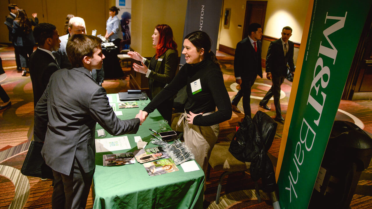 Student networking with M&T Bank representatives at GAME Forum XII.