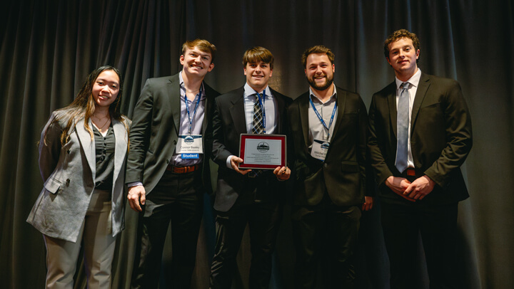 Student participants pose for a group photo with their award on stage at the GAME Forum Poster Competition Awards Ceremony.